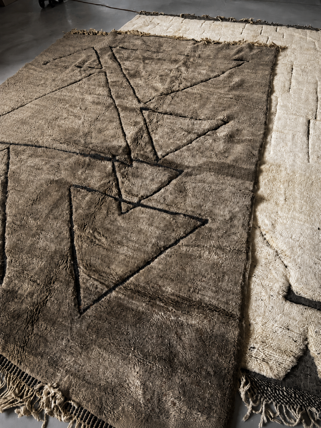 Tapis Beni M'rirt taupe à larges motifs géométriques noirs, présenté à plat.